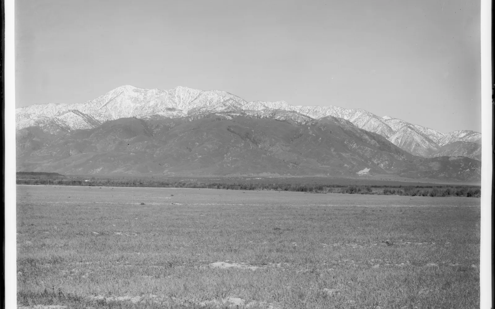 Historic photograph showing a distant view of snow-capped Mount San Antonio with surrounding landscape, circa 1920